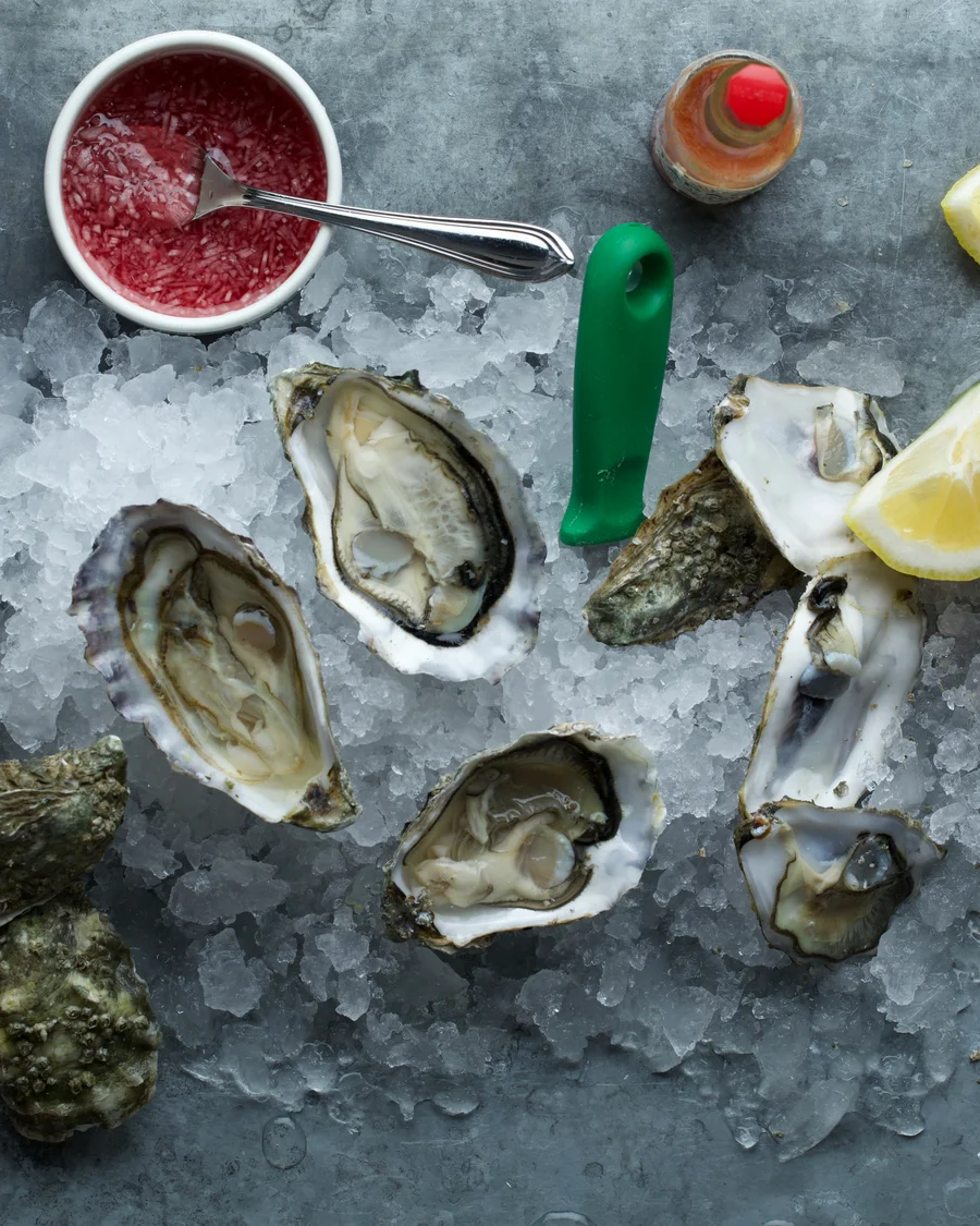 Opened oysters on crushed ice with lemon and sauces