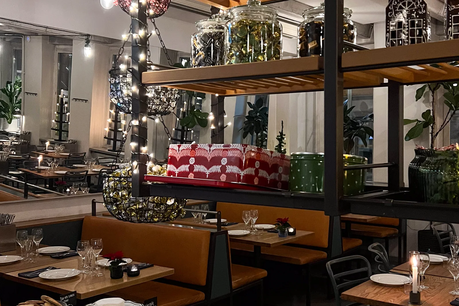 The dining room dressed for December, fairy lights over the shelving and tables laid