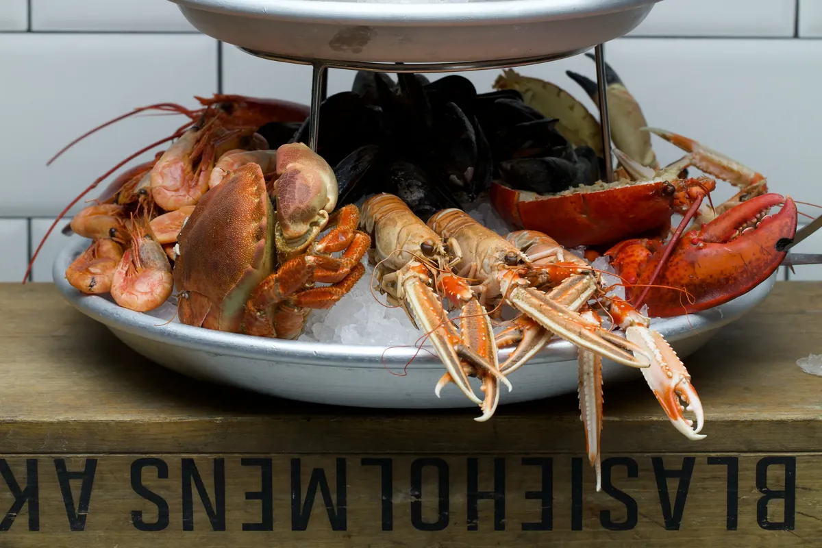 A two-tier seafood tower with shrimp, crab, mussels and lobster on ice
