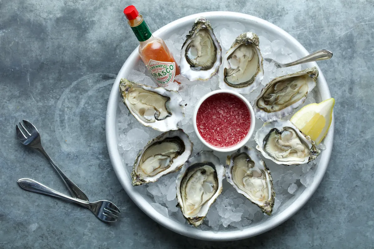 Eight opened oysters on ice with Tabasco and lemon