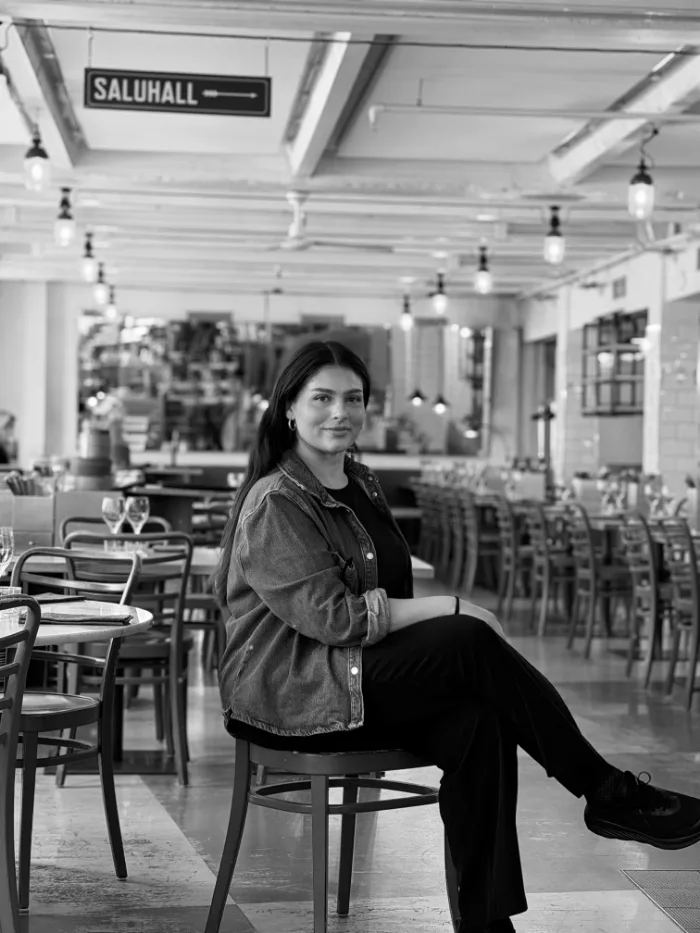 A member of the B.A.R. team in a dark jacket and dark hair, seated in the dining room under the Saluhall sign