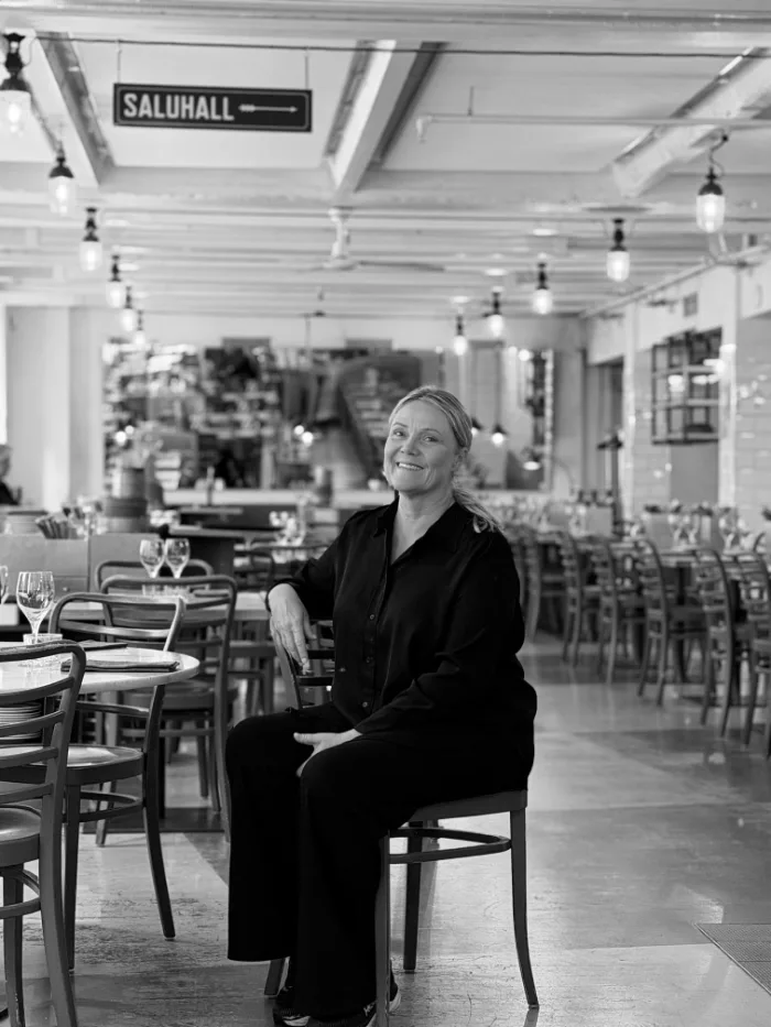 A member of the B.A.R. team in all black and fair hair, seated in the dining room under the Saluhall sign